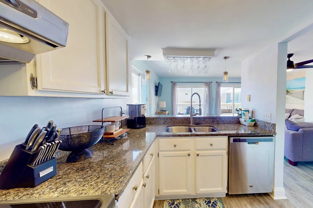 This image offers a cheerful perspective on the kitchen area, focusing on a granite countertop, kitchen sink, modern appliances, and a window that brings in natural light. It has a lively, welcoming mood and shows how cooking and entertaining can be enjoyable everyday moments in this space.